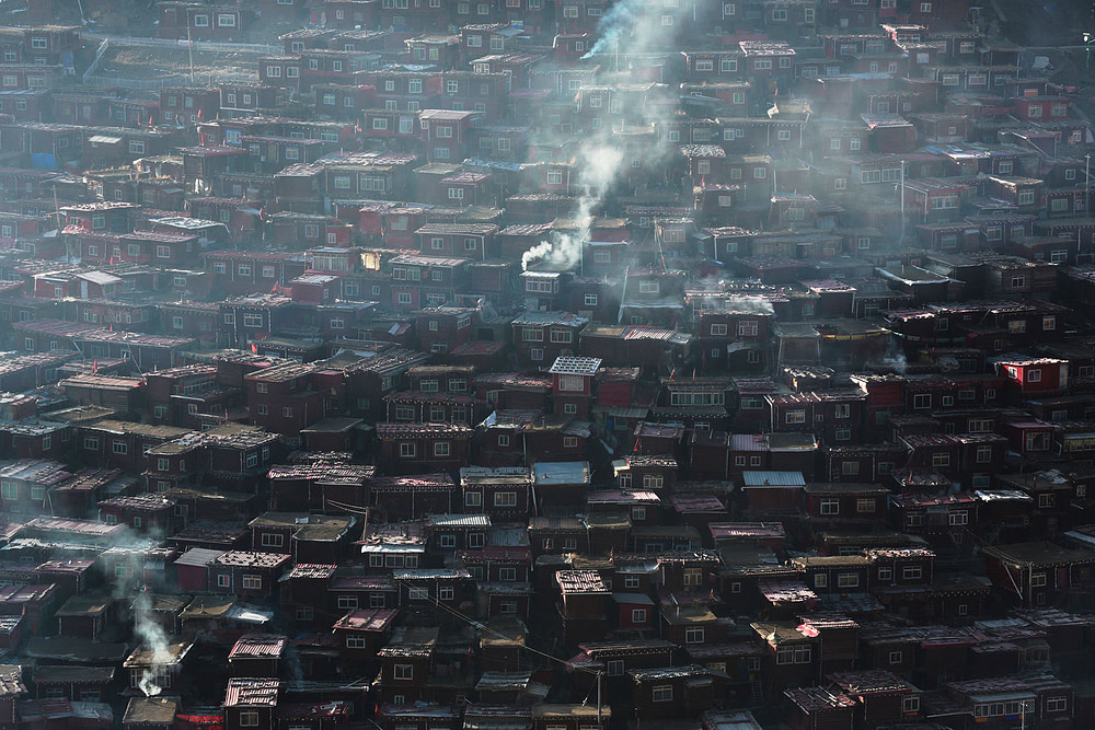 In early morning, smoke rises from the Buddhist monks’ residential area. At Larung Gar, the largest Tibetan Buddhist institute in the world, red log cabins inhabited by tens of thousands of monks cover the entire hillside.