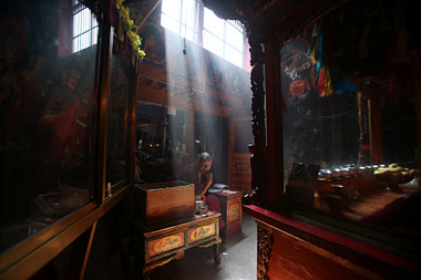 light streaming through high windows into a temple with a seated monk